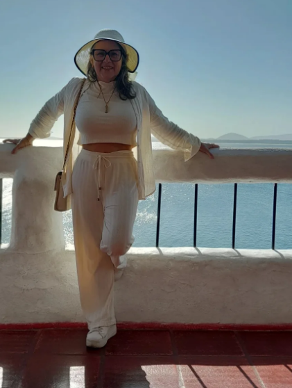 Simone de chapéu em uma varanda à beira-mar